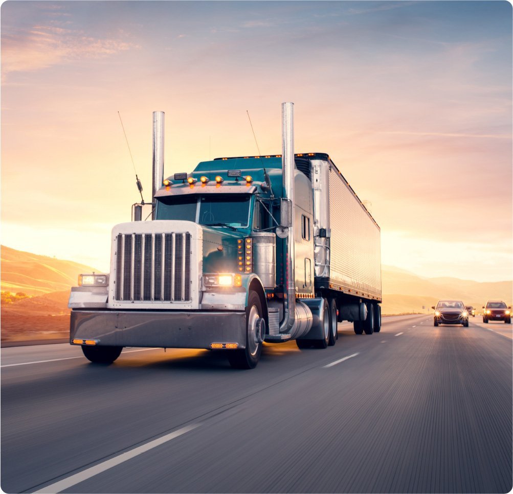 a large semi-truck traveling on a highway under clear blue skies, highlighting the importance of comprehensive trucking insurance provided by Insurance Company Westerville Ohio to protect assets and ensure the safety of the trucking industry.